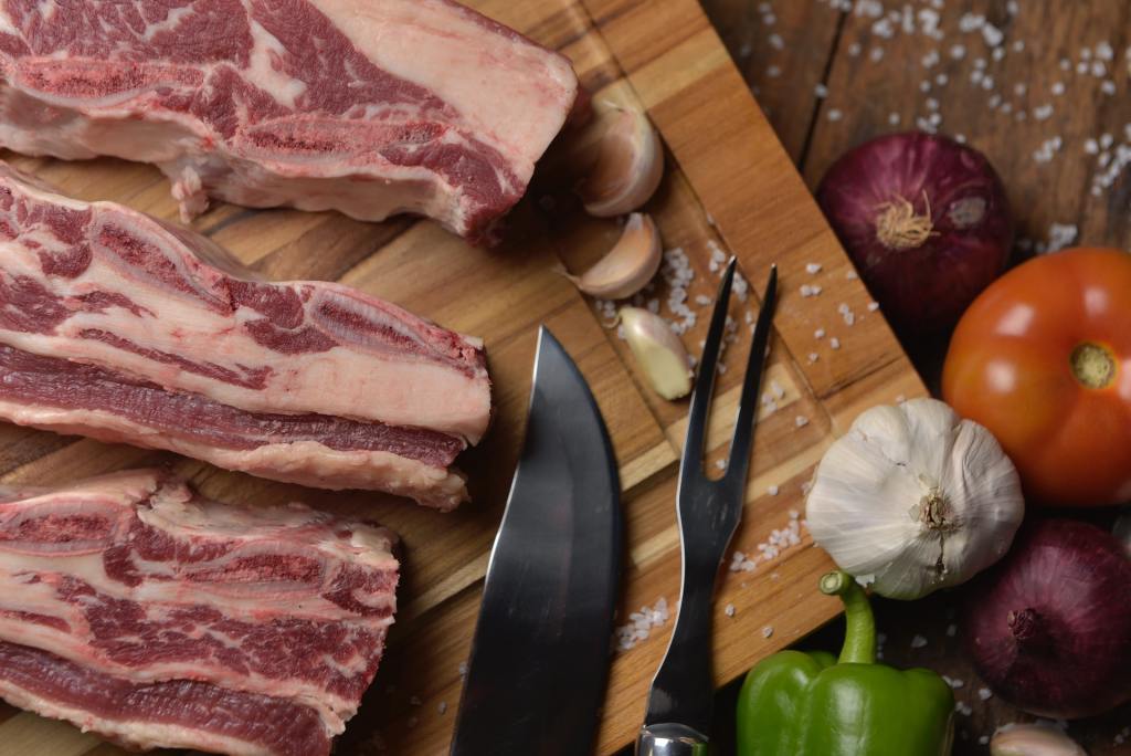 fetta di carne di maiale su un tagliere di legno con accanto le verdure
