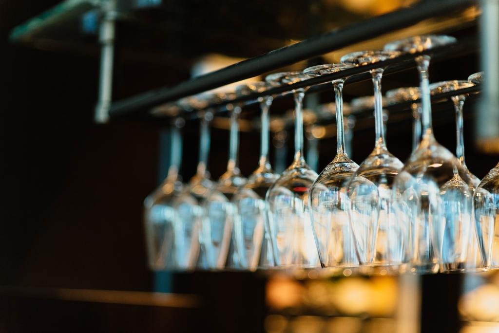 diversi bicchieri da vino appesi in una enoteca