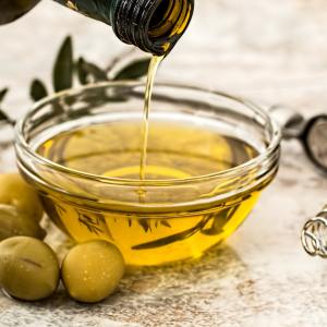 bottiglia di olio d'oliva che viene versata in una ciotola