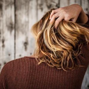 donna di spalle che si passa una mano tra i capelli