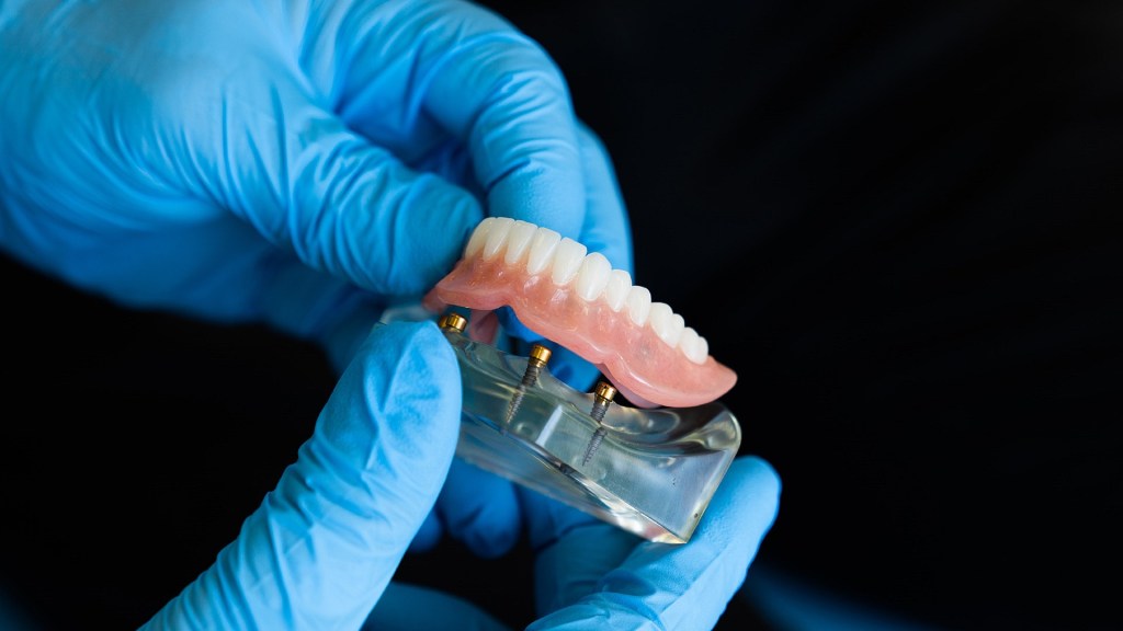 due mani con guanti che maneggiano una dentiera