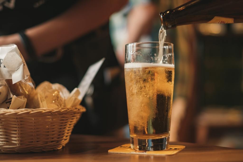 bottiglia di birra che viene versata in un bicchiere su un tavolo